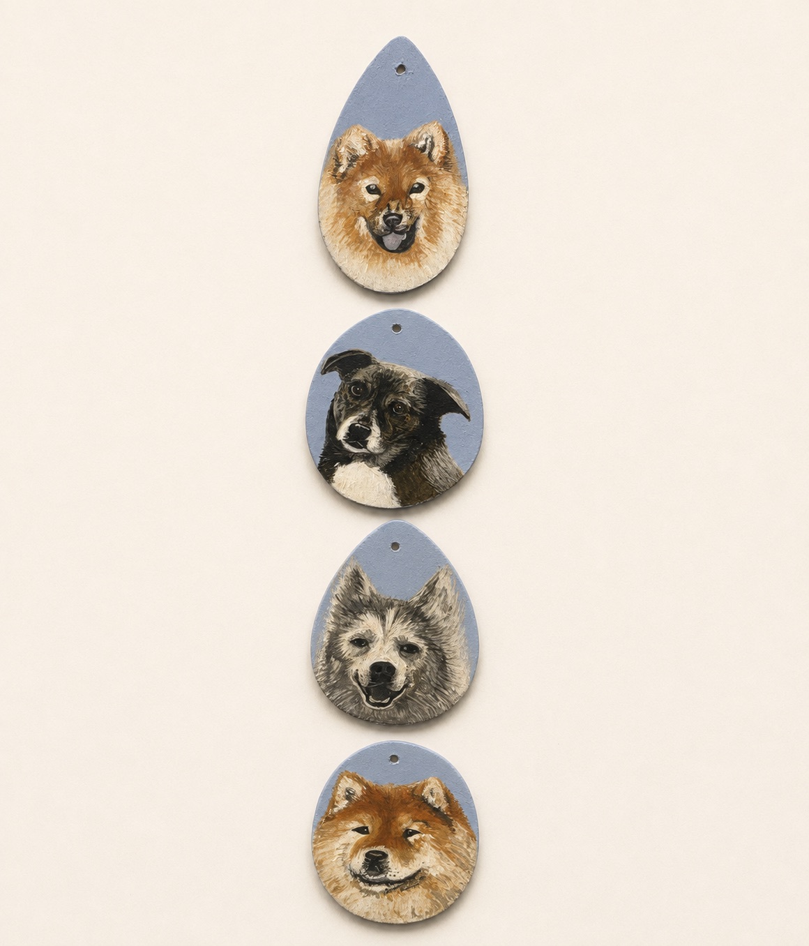 Four painted clay pendants hung in a vertical row, each with a different dog portrait